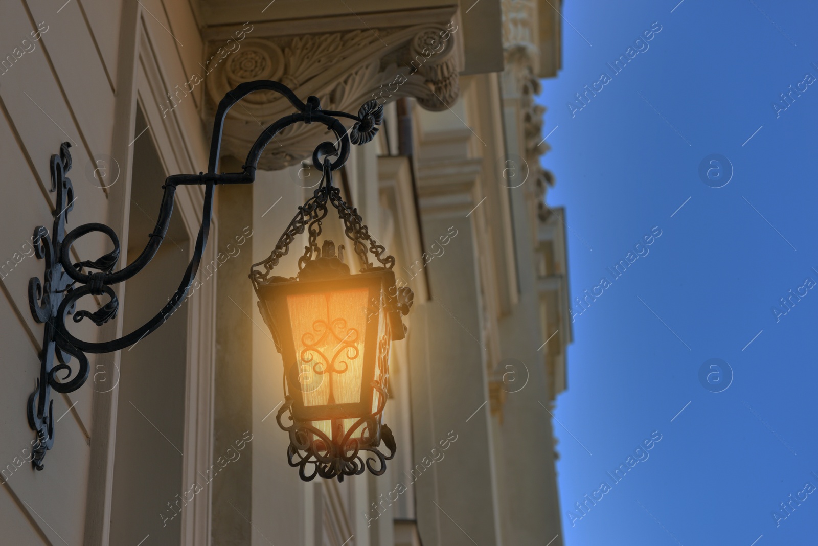 Image of Beautiful old fashioned street lamp lighting on wall of building