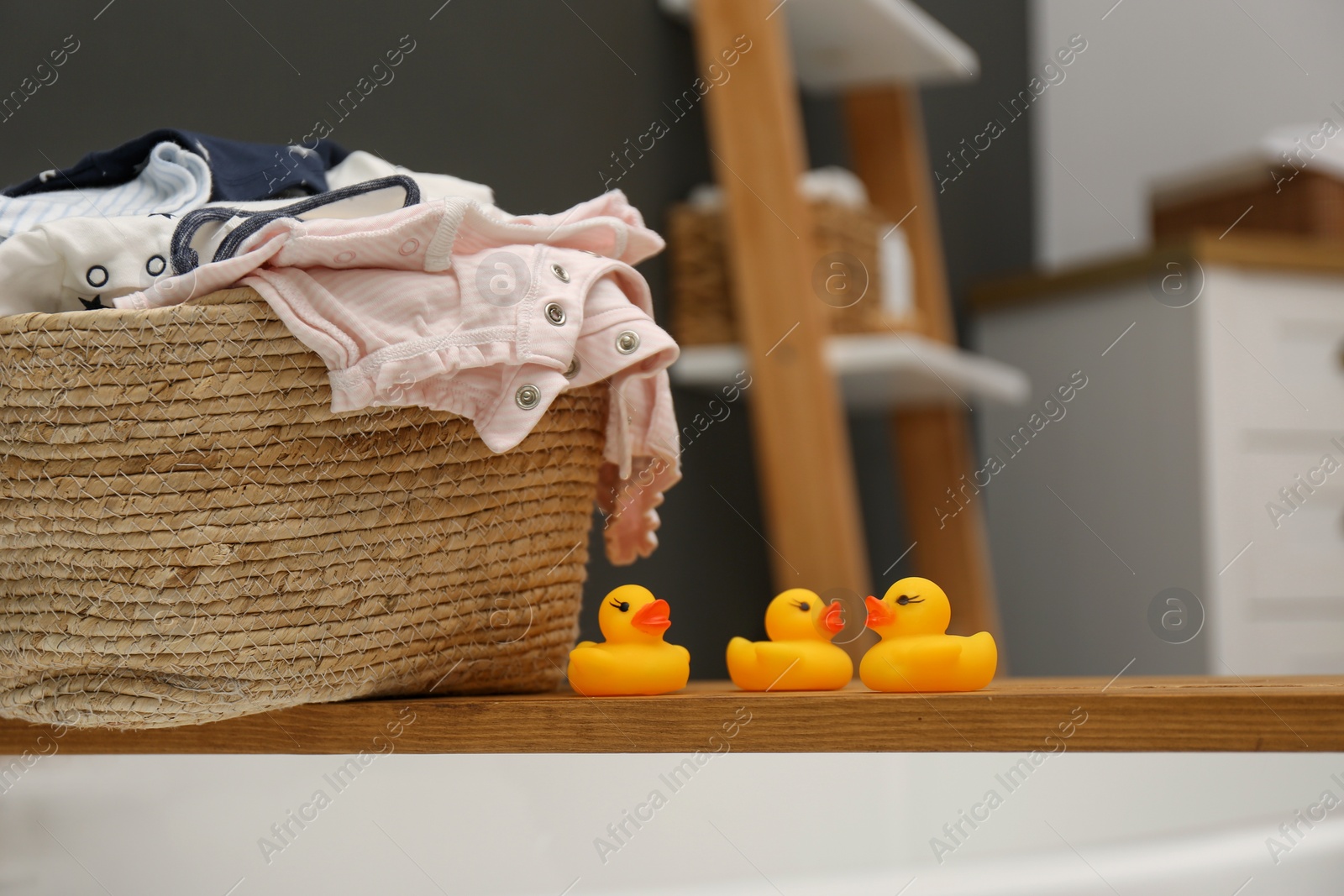 Photo of Laundry basket with baby clothes on tub tray in bathroom, closeup. Space for text