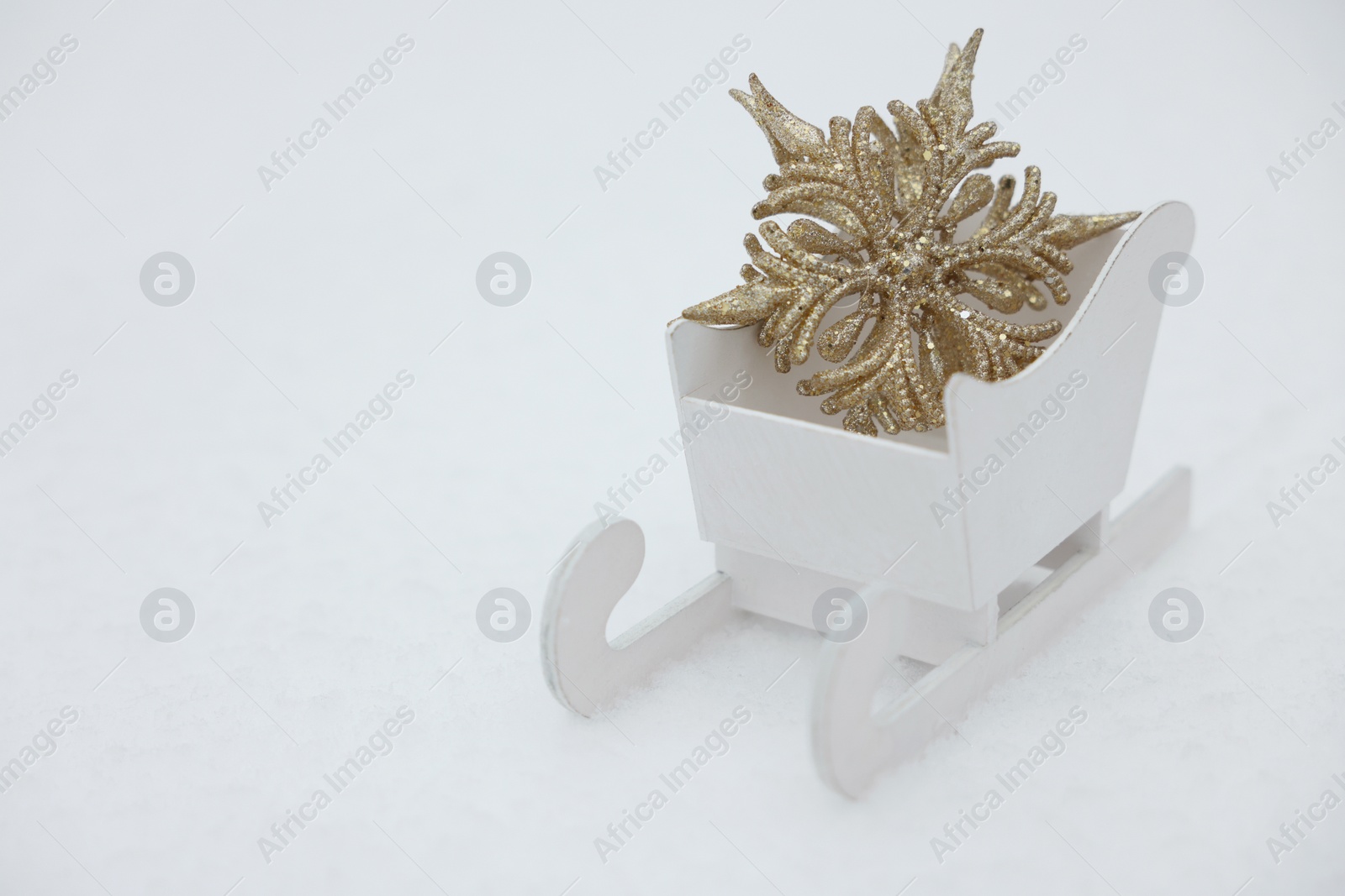 Photo of White wooden sleigh with decorative snowflake outdoors. Space for text