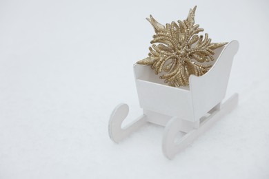 White wooden sleigh with decorative snowflake outdoors. Space for text