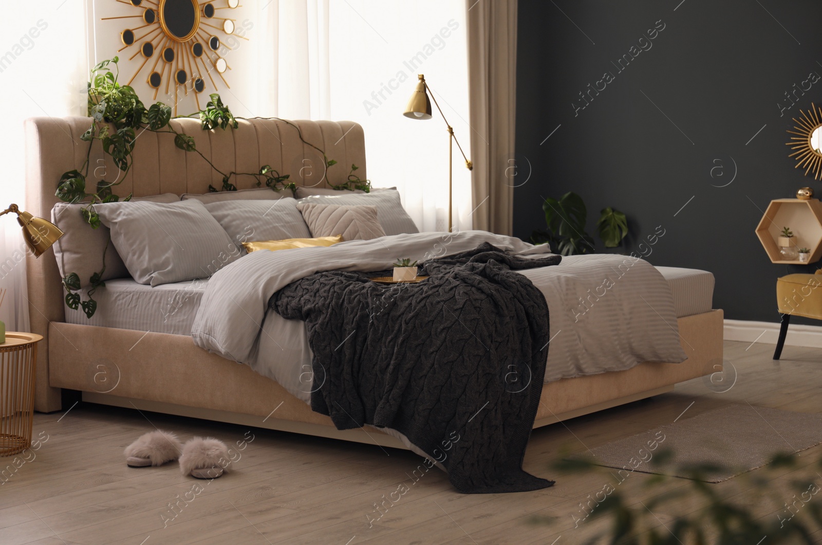 Photo of Comfortable bed with knitted black plaid in stylish room interior