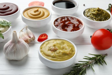 Photo of Many different sauces, spices and vegetables on white wooden table