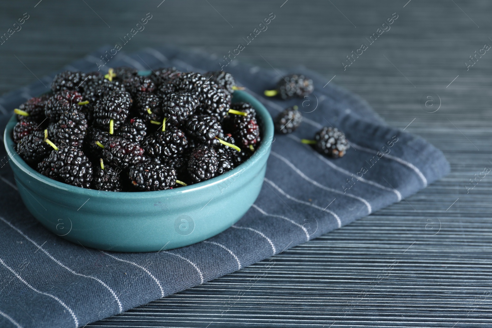 Photo of Delicious ripe black mulberries on dark wooden table, closeup. Space for text