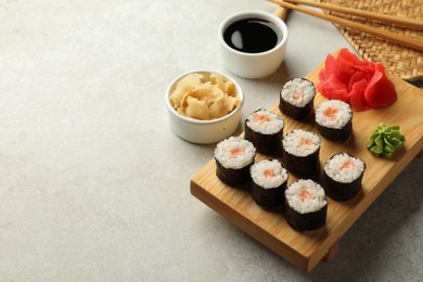 Photo of Tasty sushi rolls served on grey table. Space for text