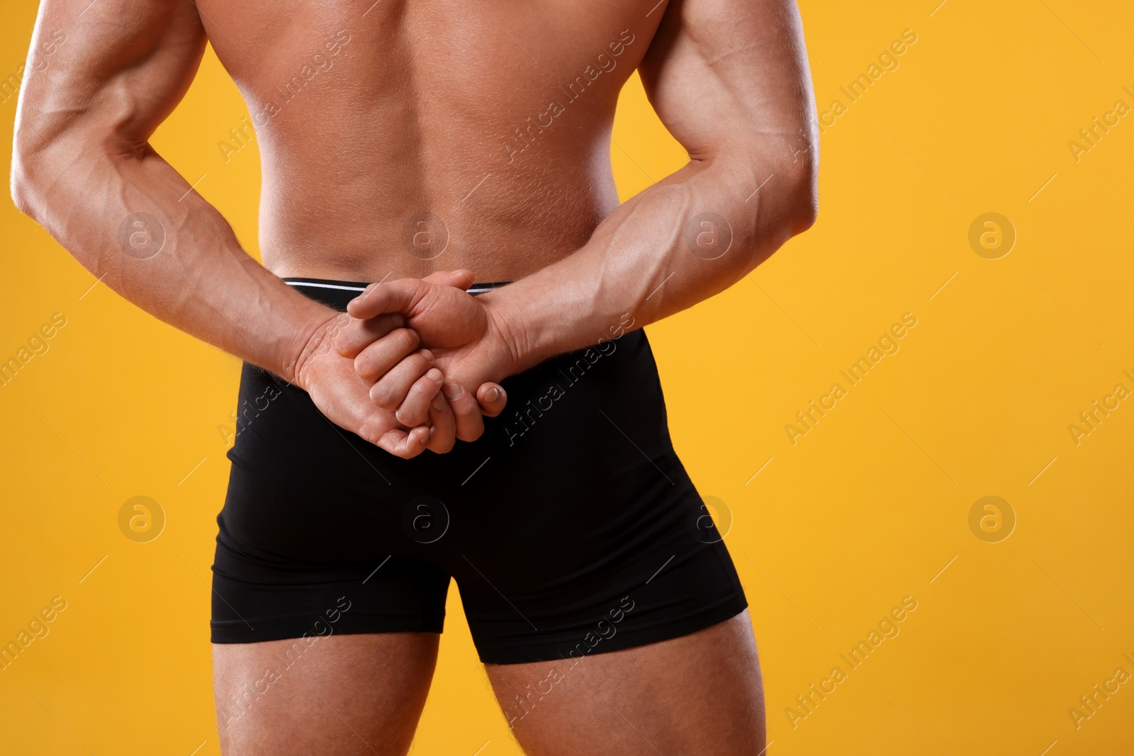 Photo of Young man is stylish black underwear on orange background, closeup