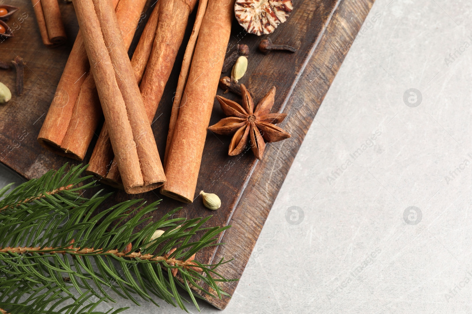 Photo of Board with different aromatic spices and fir branches on light table, top view. Space for text