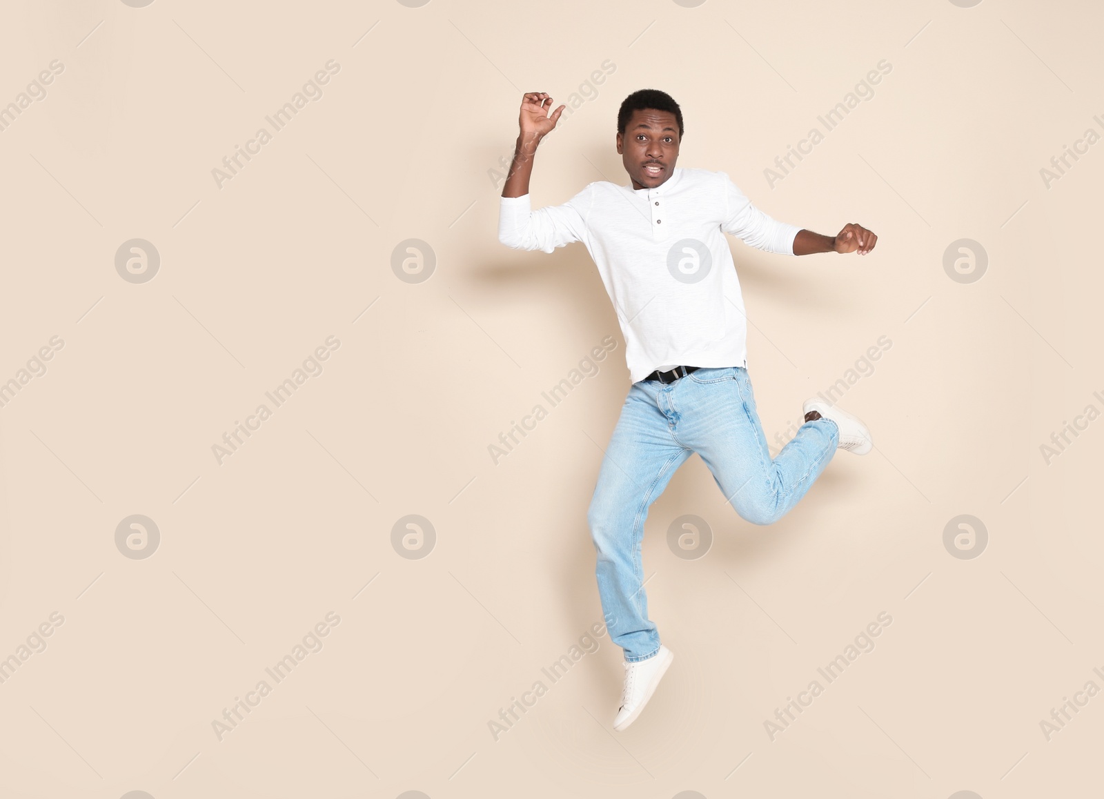 Photo of Full length portrait of African-American man jumping on color background