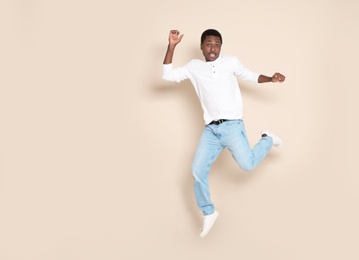 Photo of Full length portrait of African-American man jumping on color background