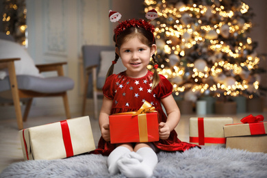 Cute little child with Christmas gift in living room
