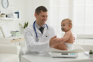 Pediatrician weighting cute little baby in clinic