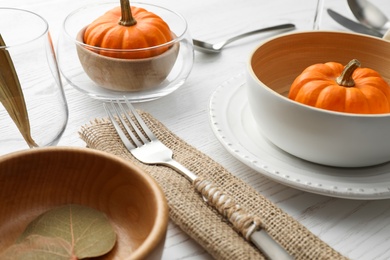 Photo of Autumn table setting with pumpkin on white wooden background, closeup