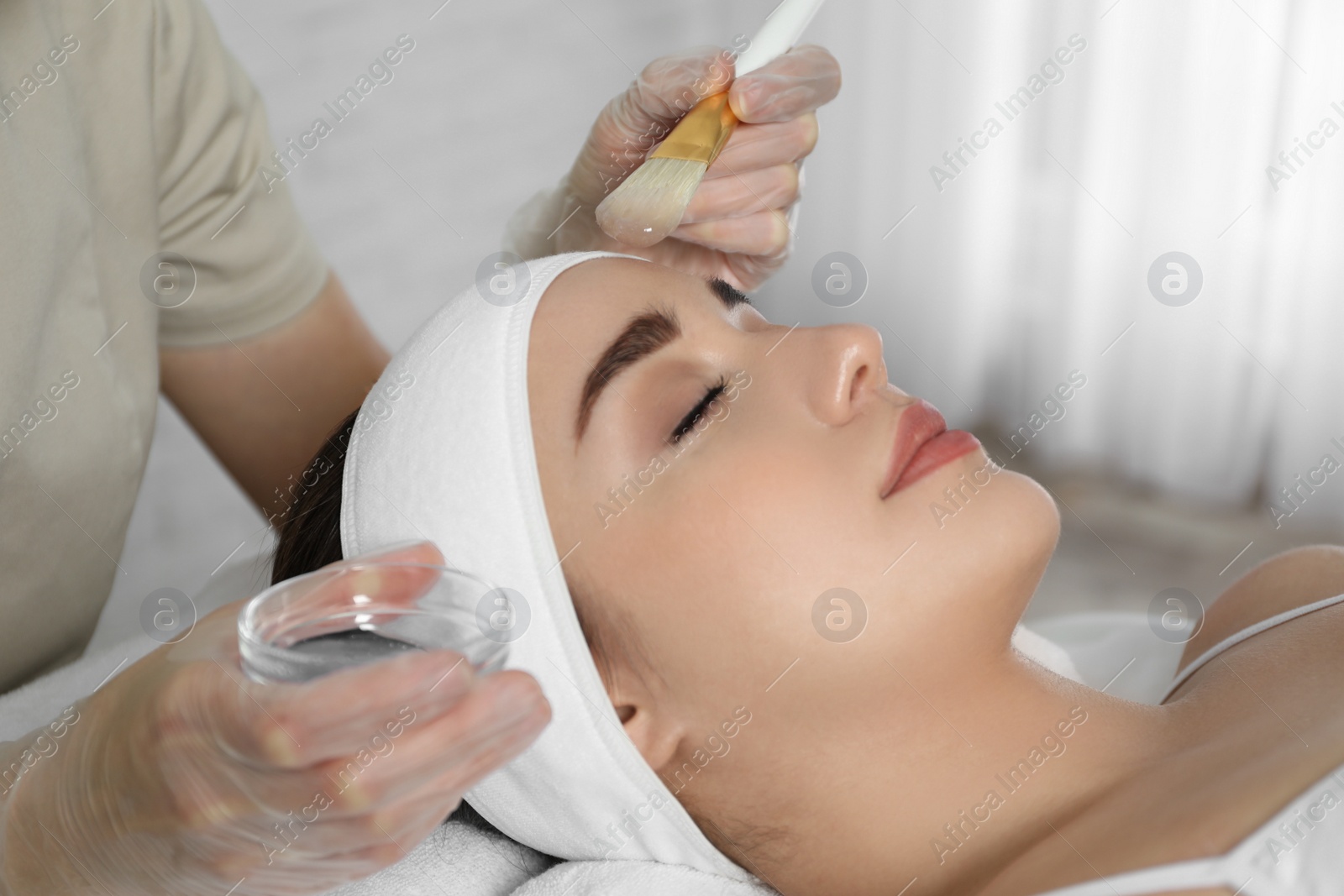 Photo of Young woman during face peeling procedure in salon