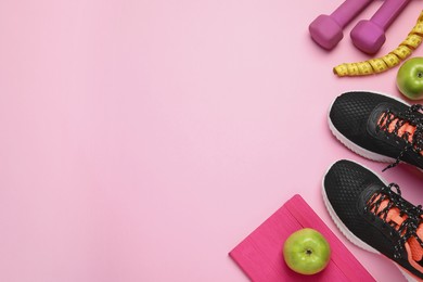 Weight loss concept. Flat lay composition with sneakers, fitness items and apples on pink background, space for text