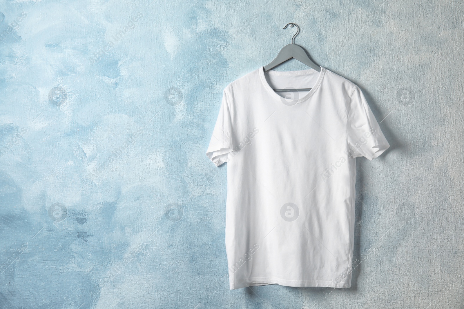 Photo of Hanger with white t-shirt on color background. Mockup for design