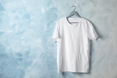 Photo of Hanger with white t-shirt on color background. Mockup for design