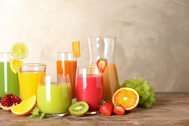 Photo of Glassware with different juices and fresh fruits on table. Space for text