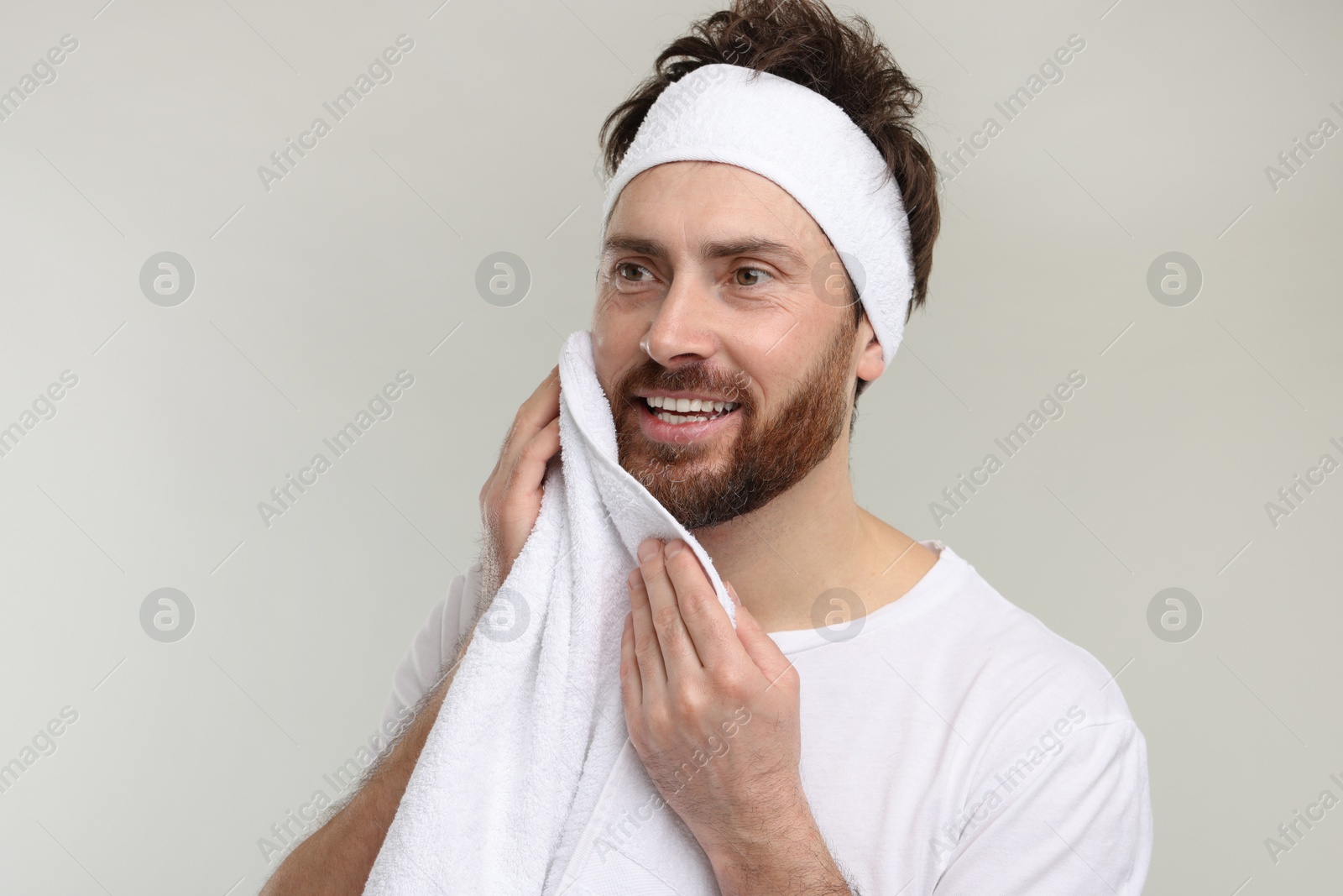 Photo of Washing face. Man with headband and towel on light grey background