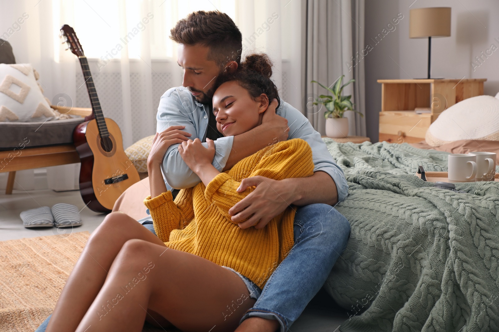 Photo of Lovely couple enjoying time together on floor in bedroom