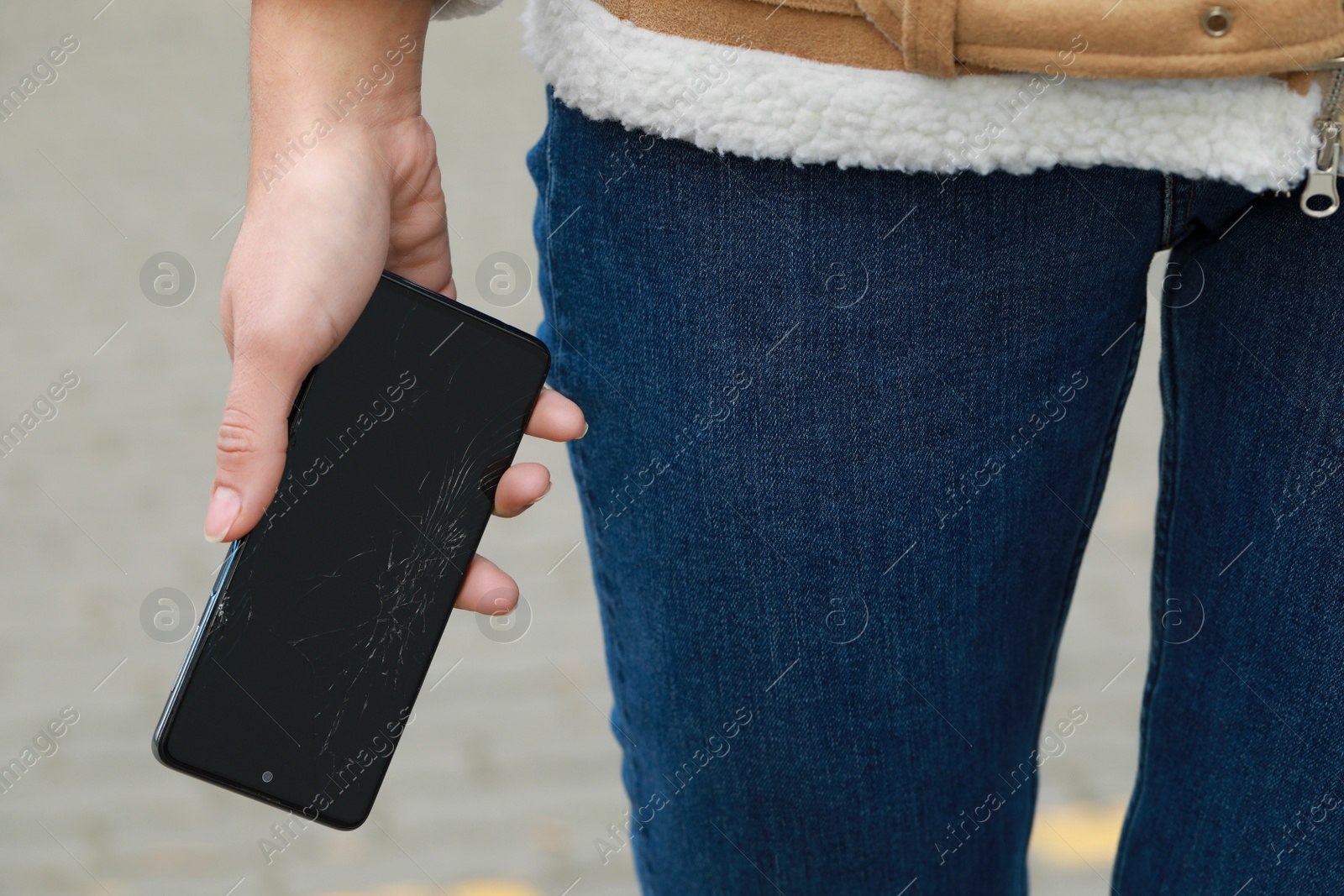 Photo of Woman holding damaged smartphone outdoors, closeup. Device repairing