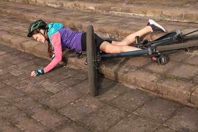 Photo of Young woman fallen off her bicycle on steps outdoors
