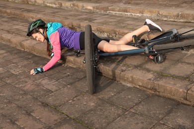 Young woman fallen off her bicycle on steps outdoors