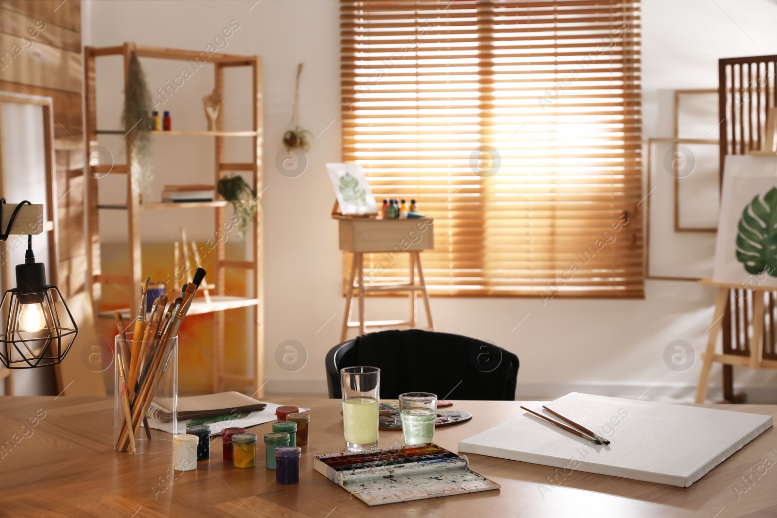 Photo of Paints and tools on wooden table in art studio