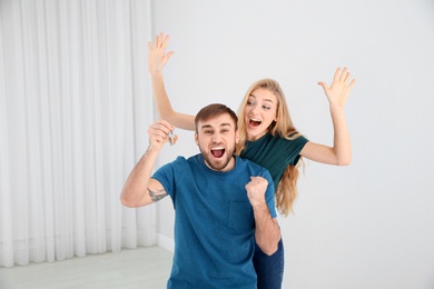 Photo of Happy young couple with key from their new house indoors