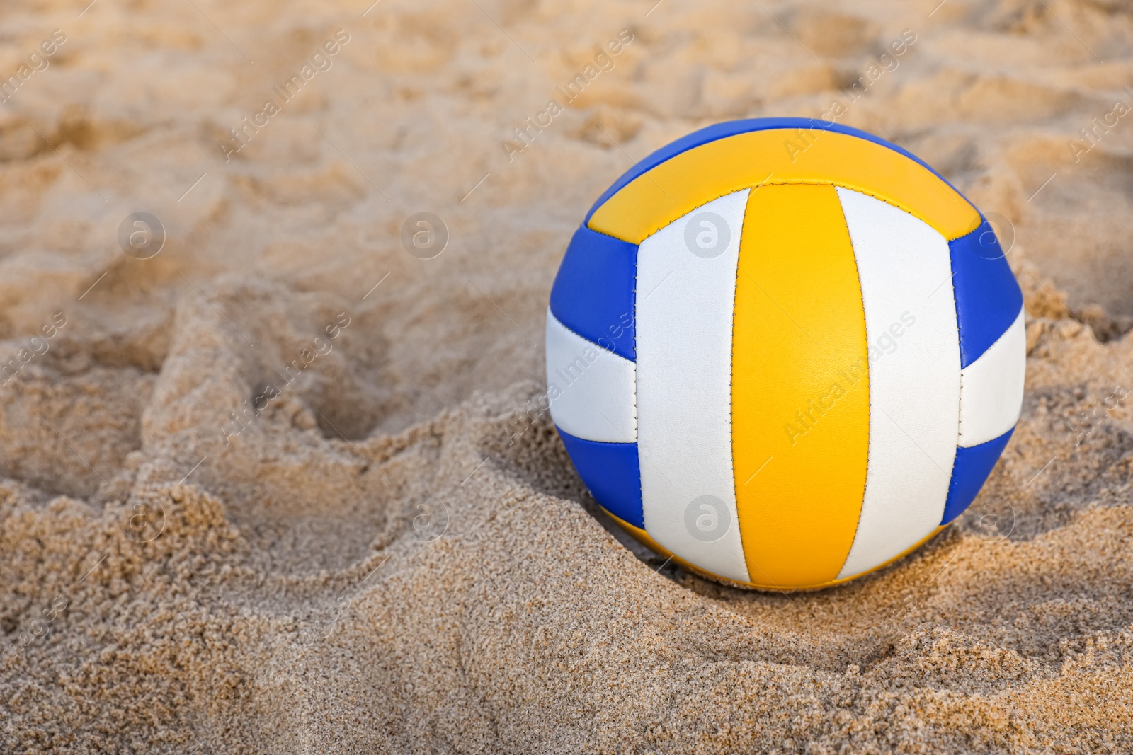 Photo of Colorful volleyball ball on sandy beach. Space for text