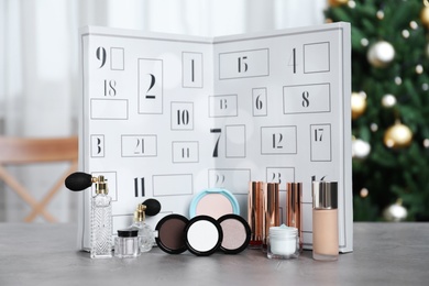 Photo of Christmas advent calendar with perfumes, skin care and decorative cosmetics on table