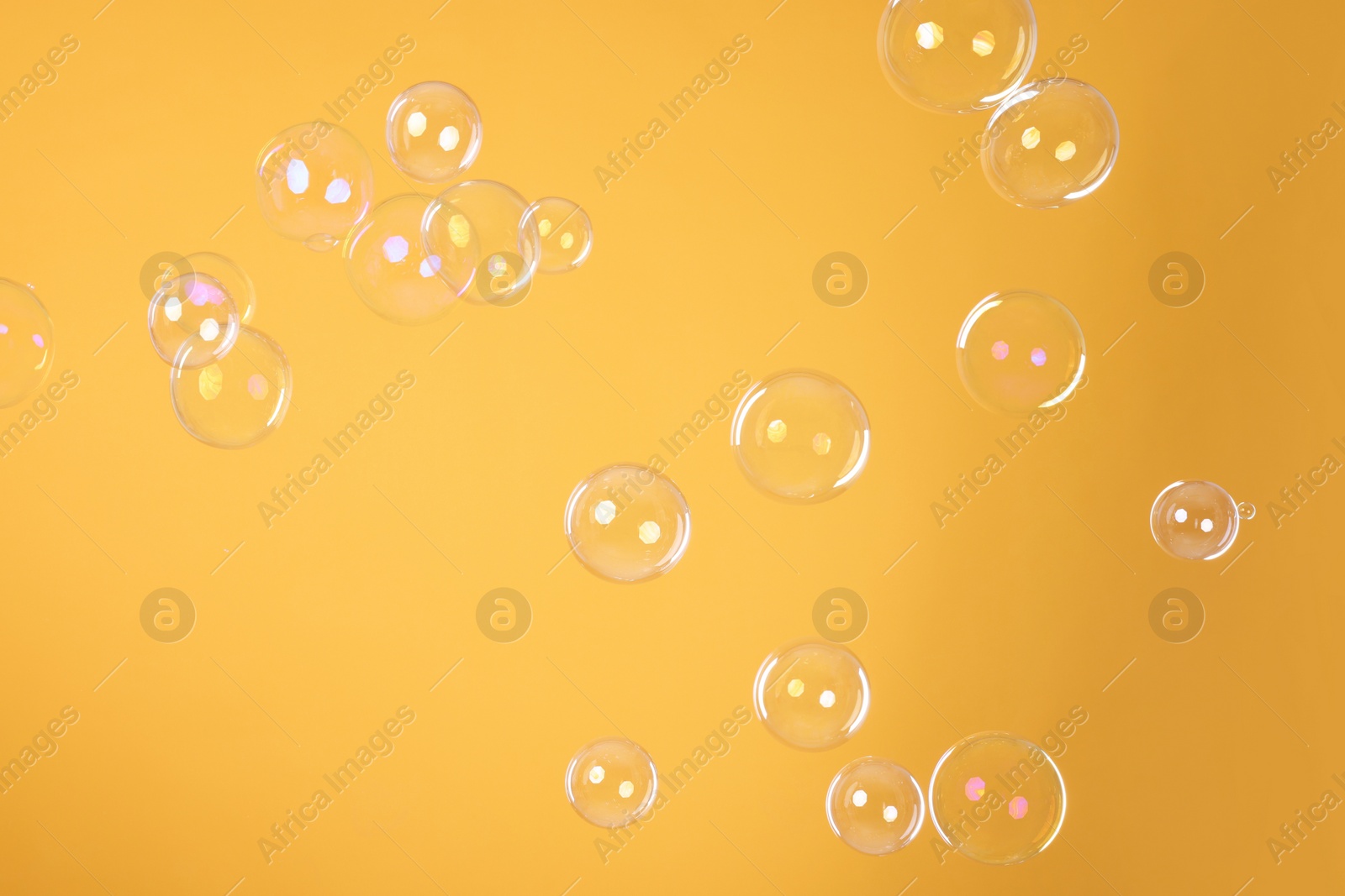 Photo of Many beautiful soap bubbles on orange background