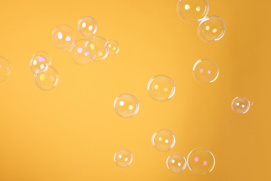 Photo of Many beautiful soap bubbles on orange background