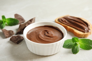 Dessert bowl with sweet chocolate cream, bread and mint on table