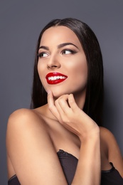 Photo of Portrait of beautiful young woman with red glossy lips on gray background