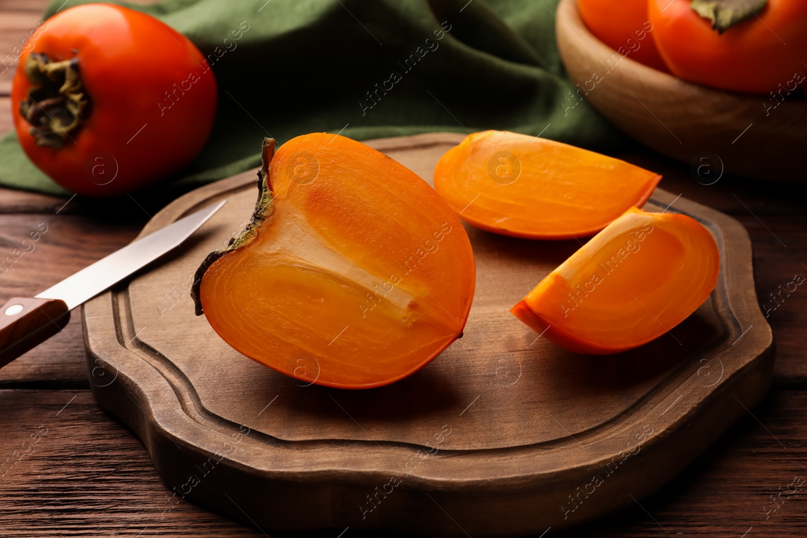Photo of Delicious ripe persimmons and knife on wooden board