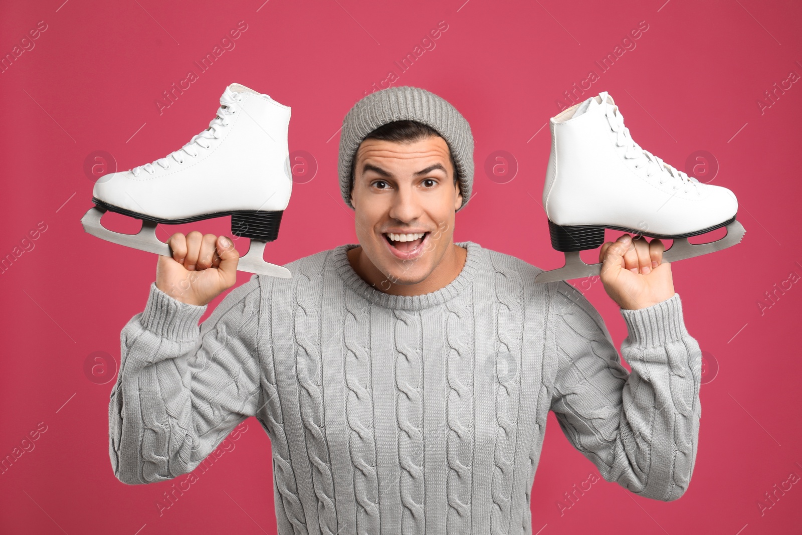 Photo of Emotional man with ice skates on pink background