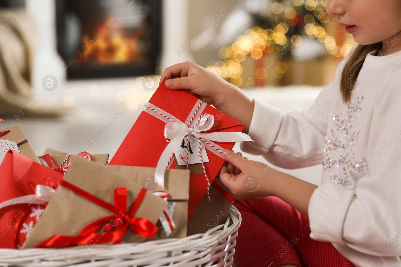 Photo of Little girl taking gift from Christmas advent calendar at home, closeup