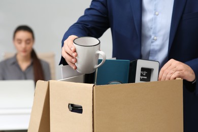 Photo of Dismissed man packing personal stuff into box in office, closeup