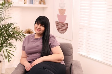 Photo of Beautiful overweight woman sitting in armchair at home
