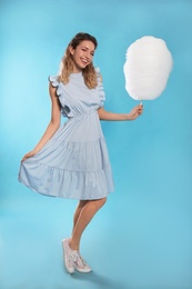 Photo of Full length portrait of pretty young woman with tasty cotton candy on blue background