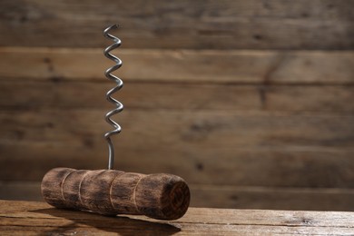 One corkscrew on wooden table, closeup. Space for text