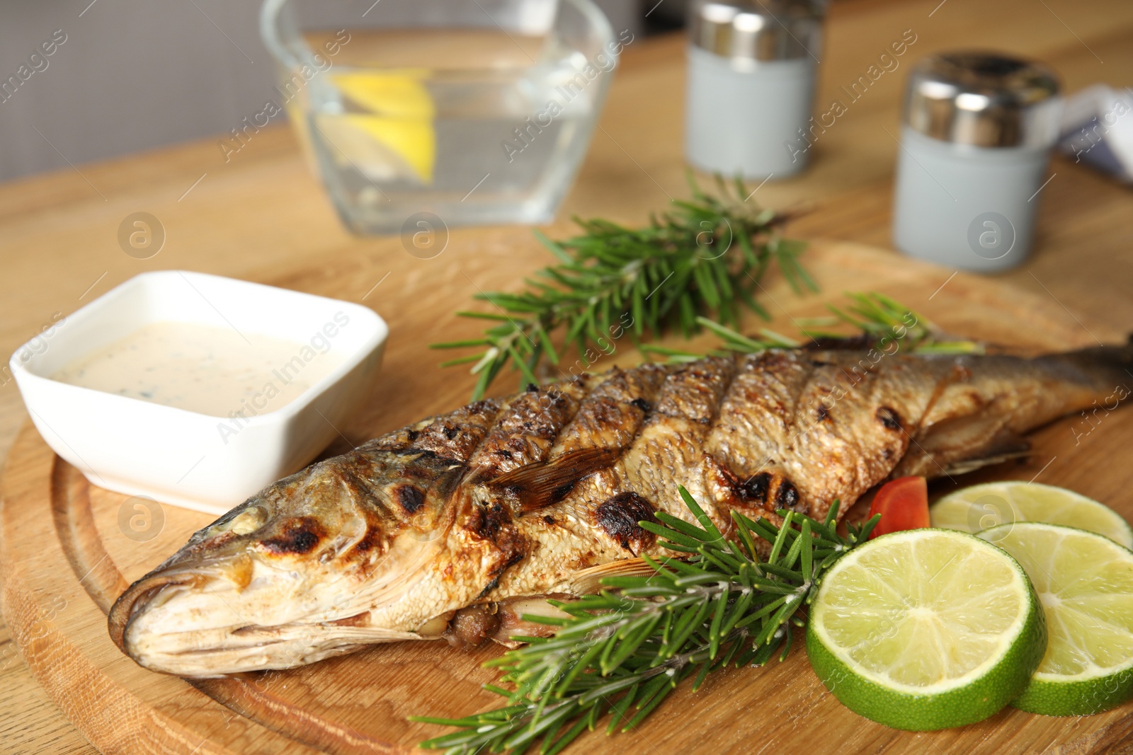 Photo of Delicious grilled fish with lime on wooden board, closeup