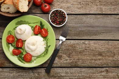 Photo of Delicious burrata cheese with arugula and tomatoes on wooden table, flat lay. Space for text