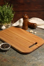 Photo of Wooden cutting board and spices on textured table, closeup
