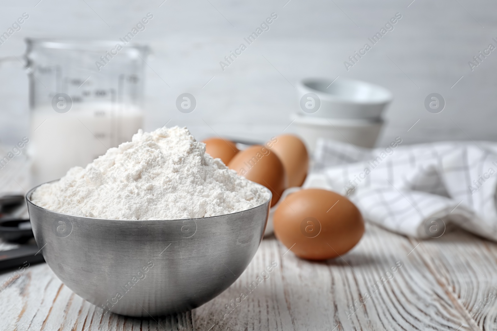 Photo of Bowl with flour on wooden table