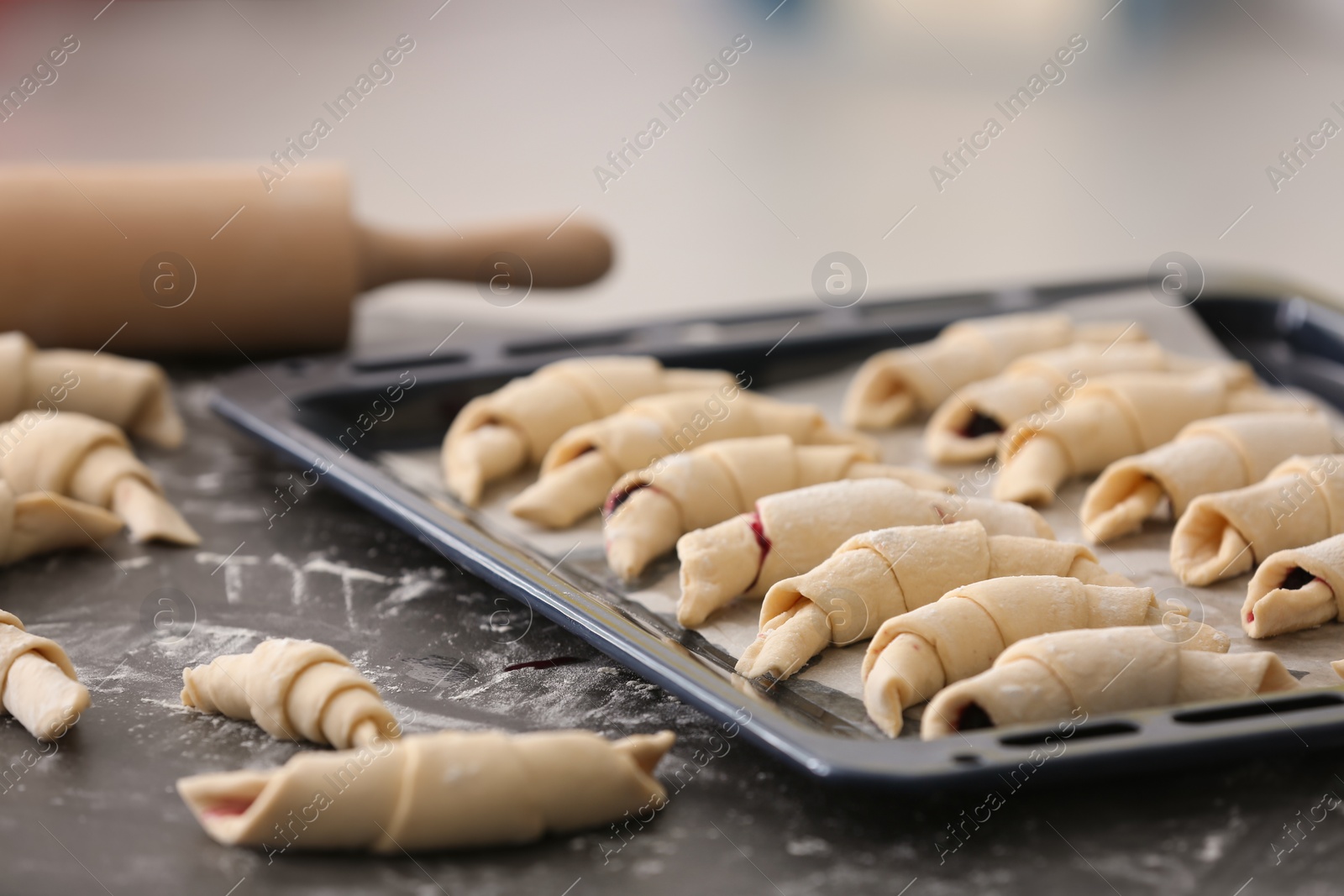 Photo of Baking sheet with raw croissants on table