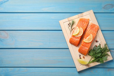 Photo of Fresh salmon and ingredients for marinade on light blue wooden table, top view. Space for text
