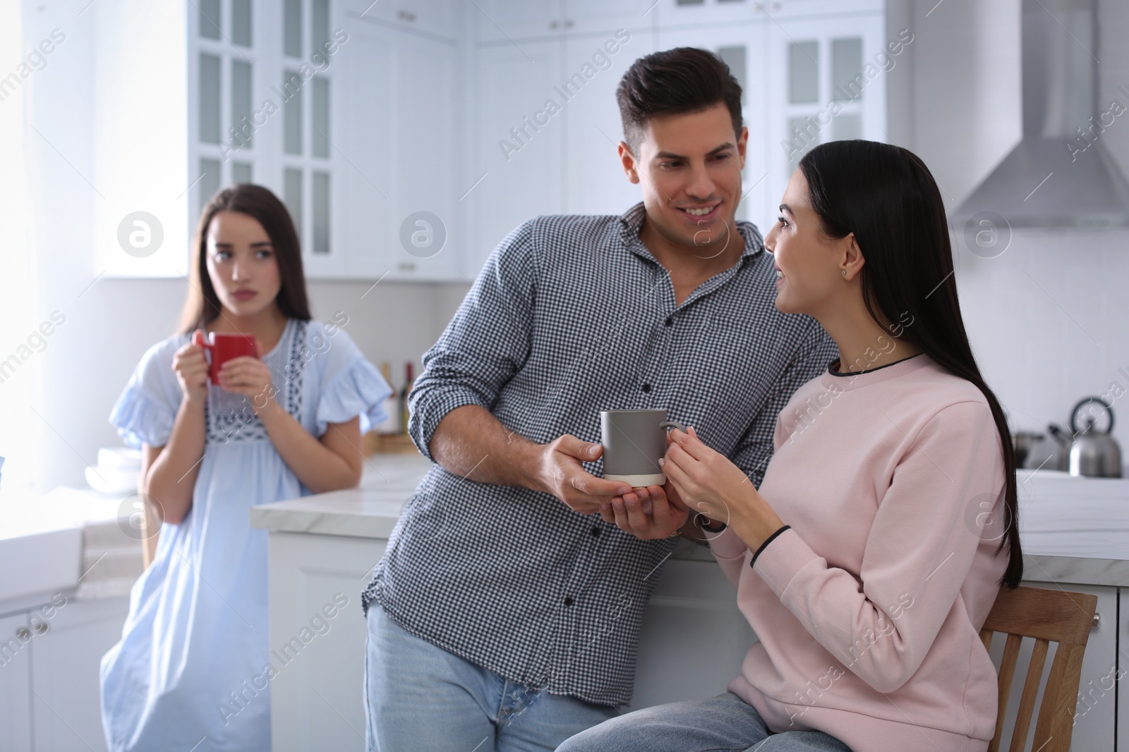 Photo of Unhappy woman feeling jealous while couple spending time together in kitchen