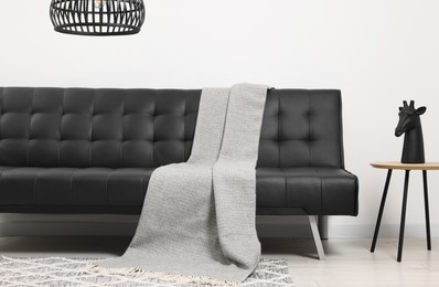 Comfortable sofa, blanket and side table in living room