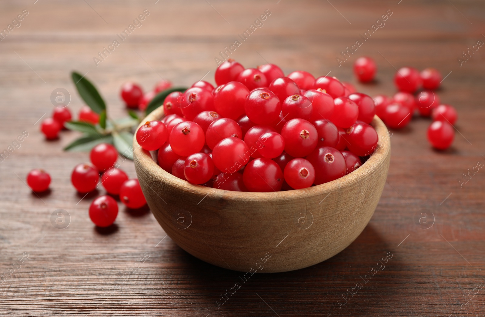 Photo of Tasty ripe cranberries on brown wooden table, closeup