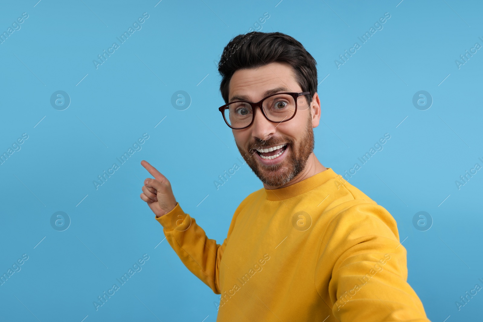 Photo of Smiling man taking selfie on light blue background